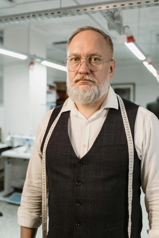 a man with a beard standing in an office, overalls and a white beard, pawel rebisz, tailored clothing, pictured from the shoulders up