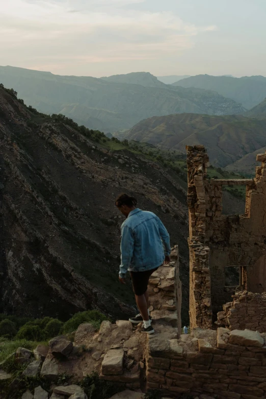 a man standing at the top of a mountain, les nabis, crumbling buildings, walking away from camera, 8 k movie still, moroccan