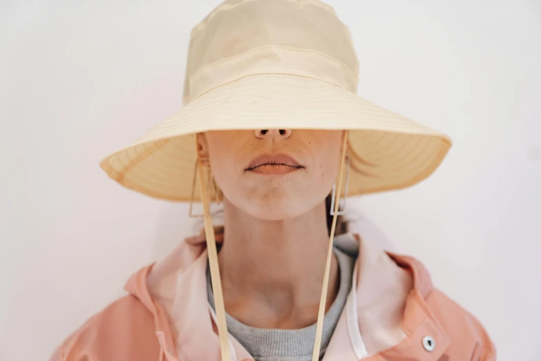 a close up of a person wearing a hat, by Nina Hamnett, trending on pexels, girl in raincoat, light tan, lemonade, visor over face