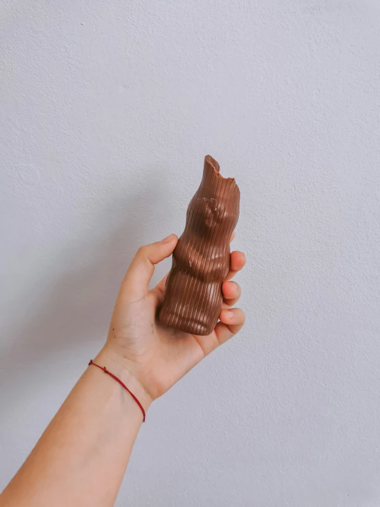 a person holding a piece of chocolate in their hand, a surrealist sculpture, by Andrée Ruellan, cat bunny, medium long shot, guanyin, soft curvy shape