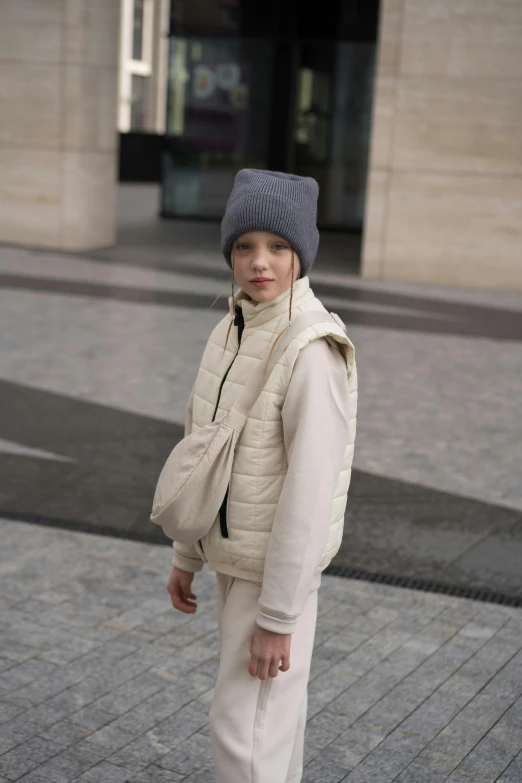 a woman riding a skateboard down a sidewalk, by Nina Hamnett, happening, model wears a puffer jacket, boy with neutral face, beige, photographed for reuters