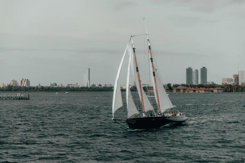 a sailboat in the water with a city in the background, toronto city, high-quality photo, fan favorite, medium shot angle