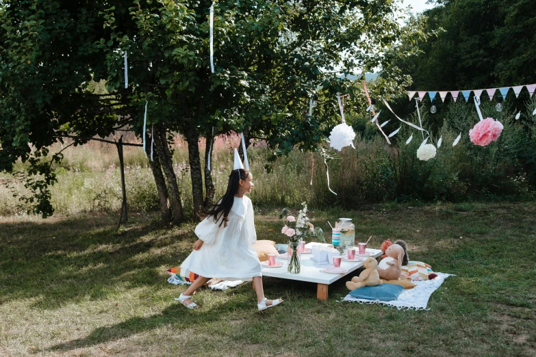 a woman in a white dress standing next to a picnic table, by Julia Pishtar, pexels contest winner, kids playing, having a cool party, sitting on a table, floating away