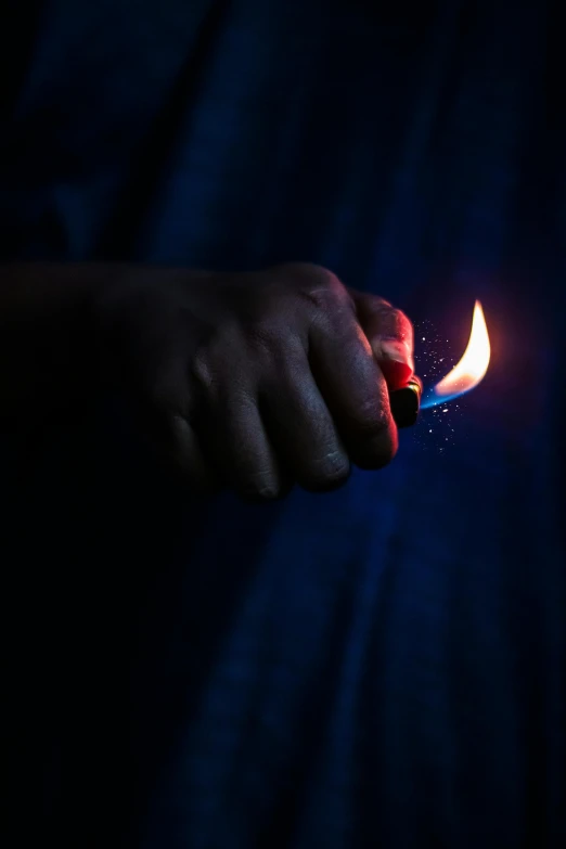 a person holding a lit lighter in their hand, by James Warhola, dark blue and red, photograph taken in 2 0 2 0, fires, battered