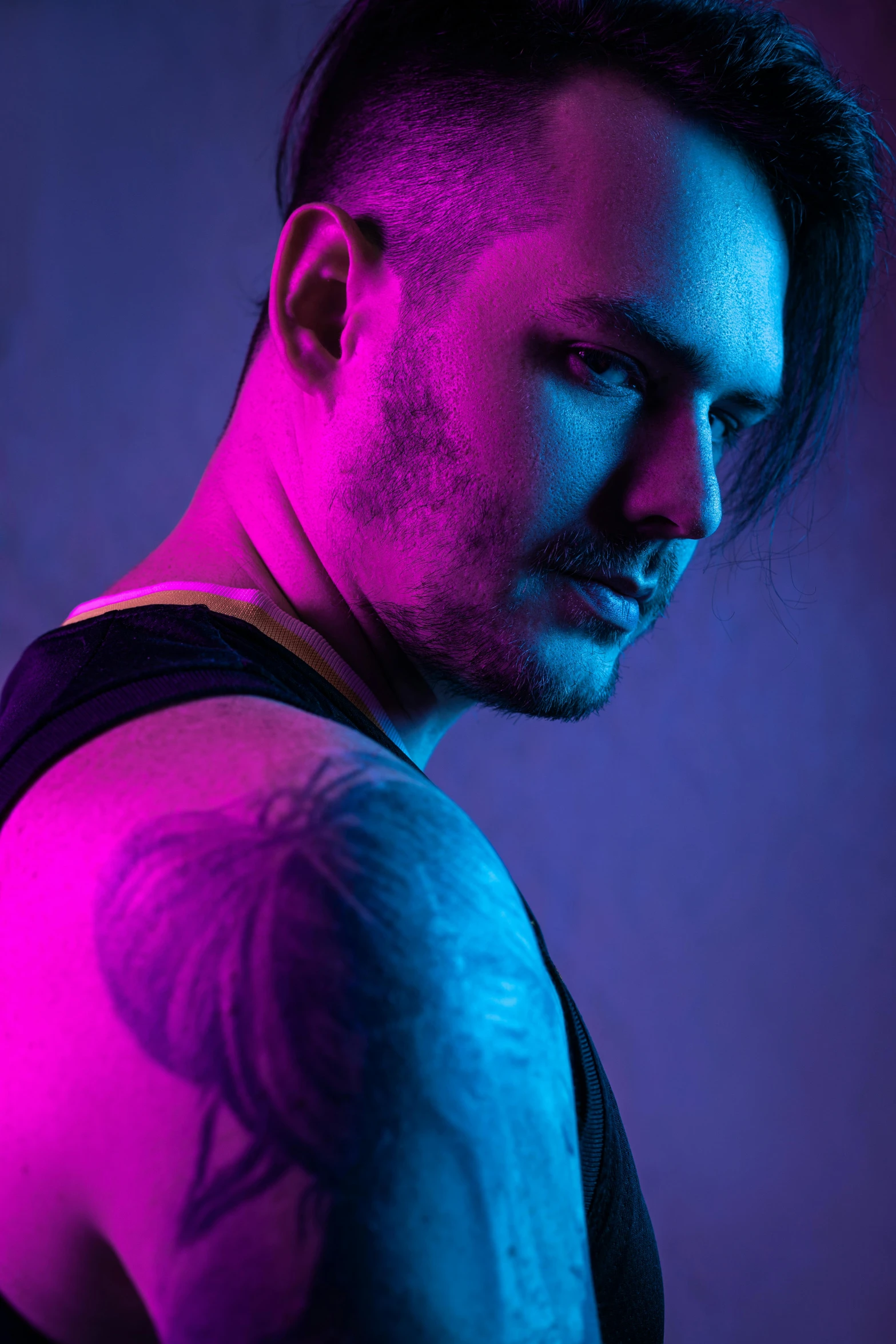 a man with a tattoo on his arm, an album cover, inspired by Camilo Egas, trending on pexels, soft neon purple lighting, studio!! portrait lighting, wearing a low cut tanktop, killian eng