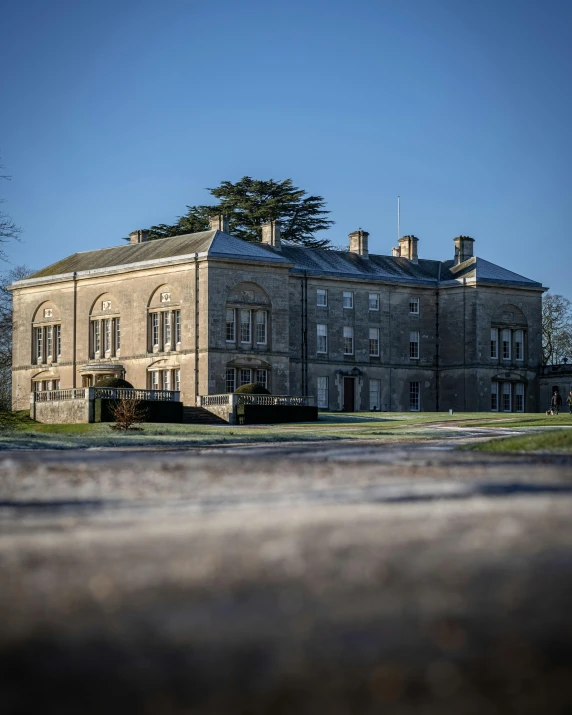 a large stone building sitting on top of a lush green field, by Rachel Reckitt, winter, halls, exterior photo, thumbnail