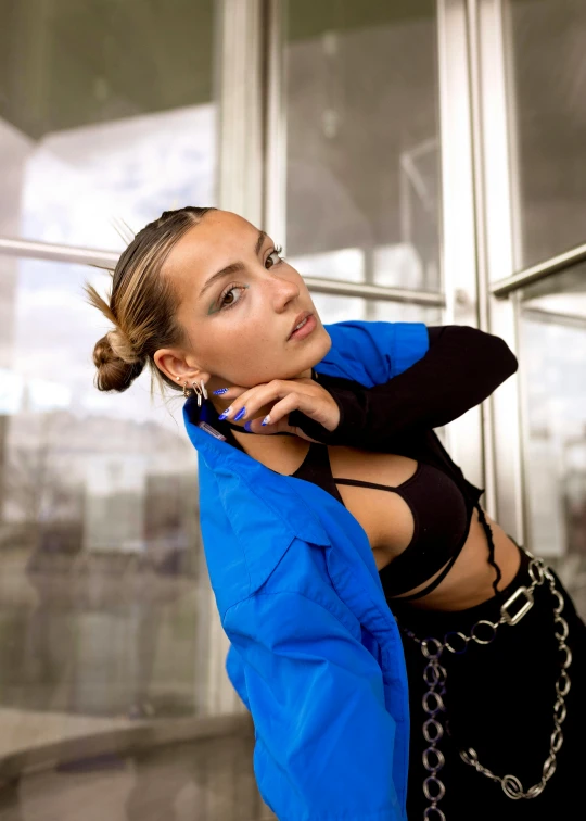 a woman in a blue jacket talking on a cell phone, an album cover, by Julia Pishtar, unsplash, renaissance, wearing a crop top, pose model, double long braids blue, leaning on door