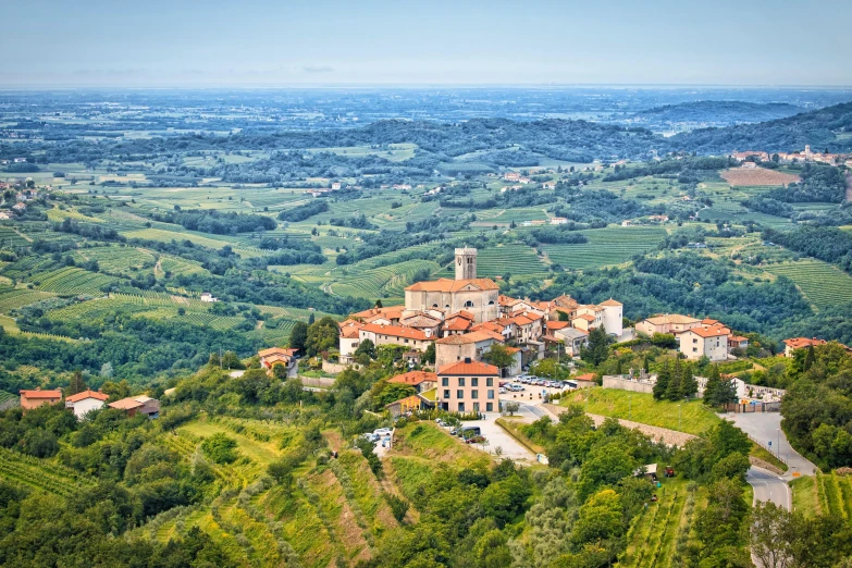 a large building sitting on top of a lush green hillside, by Carlo Martini, pexels contest winner, renaissance, view of villages, wine, square, jeszika le vye