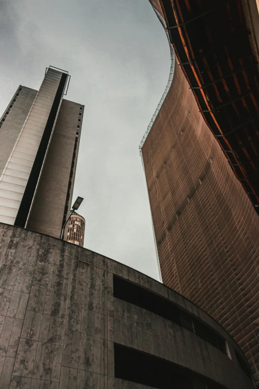 a couple of tall buildings next to each other, by Carlo Martini, pexels contest winner, brutalism, churches, rusted walls, curving, high quality photo