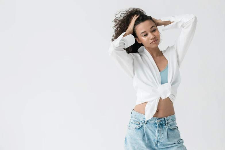 a woman in a white shirt and blue jeans, inspired by Esaias Boursse, trending on unsplash, doja cat, female dancer, white backdrop, button up shirt