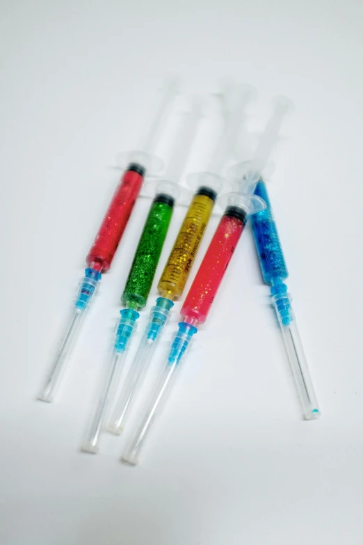 a bunch of toothbrushes sitting on top of a table, glitter gif, with an iv drip, 5 colors, transparent liquid