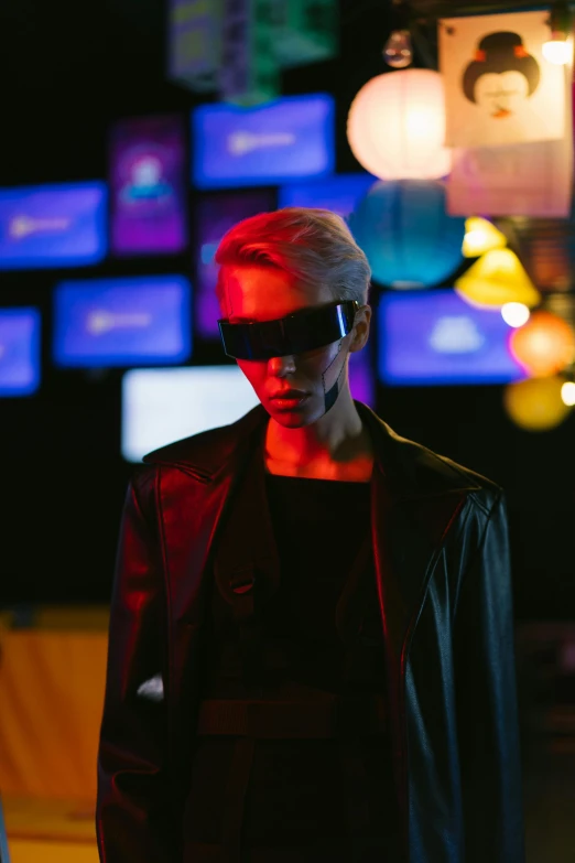 a woman standing in front of a bunch of television screens, by Nick Fudge, trending on pexels, wearing cyberpunk leather jacket, dark shades, non binary model, john carmack