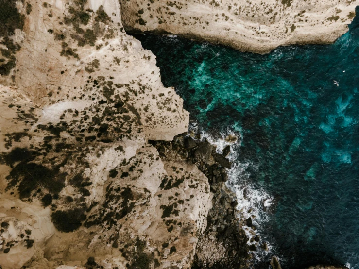 a group of people standing on top of a cliff next to the ocean, pexels contest winner, les nabis, close-up from above, cyprus, teal aesthetic, water texture
