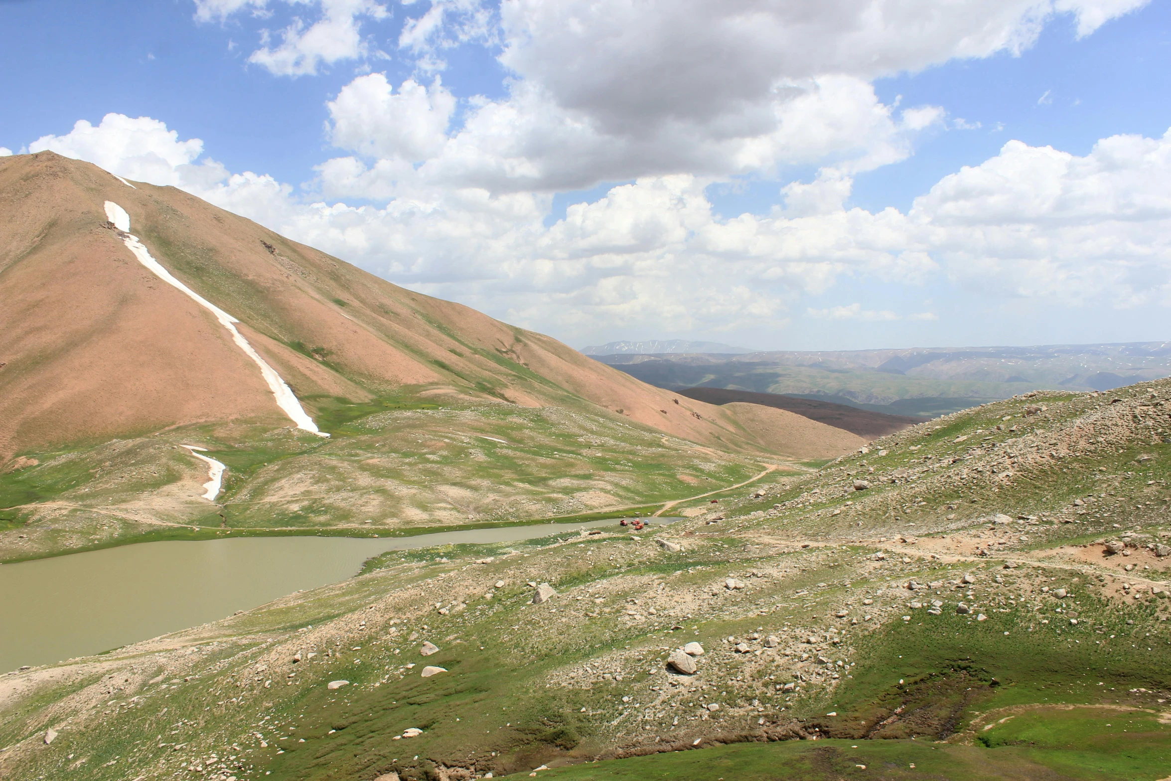 a body of water sitting on top of a lush green hillside, by Abdullah Gërguri, trending on unsplash, les nabis, afshar, red peaks in the background, 2000s photo, multiple stories