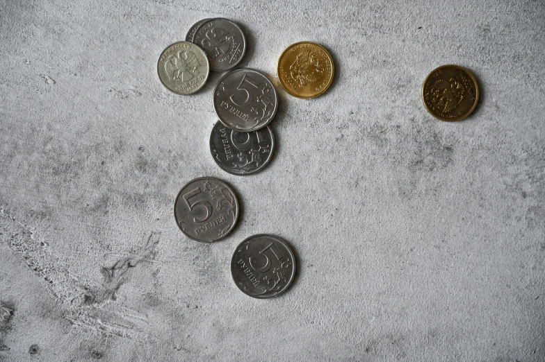 a pile of coins sitting on top of a table, by Emma Andijewska, pexels contest winner, bauhaus, gray concrete, flatlay, tallinn, wall corner