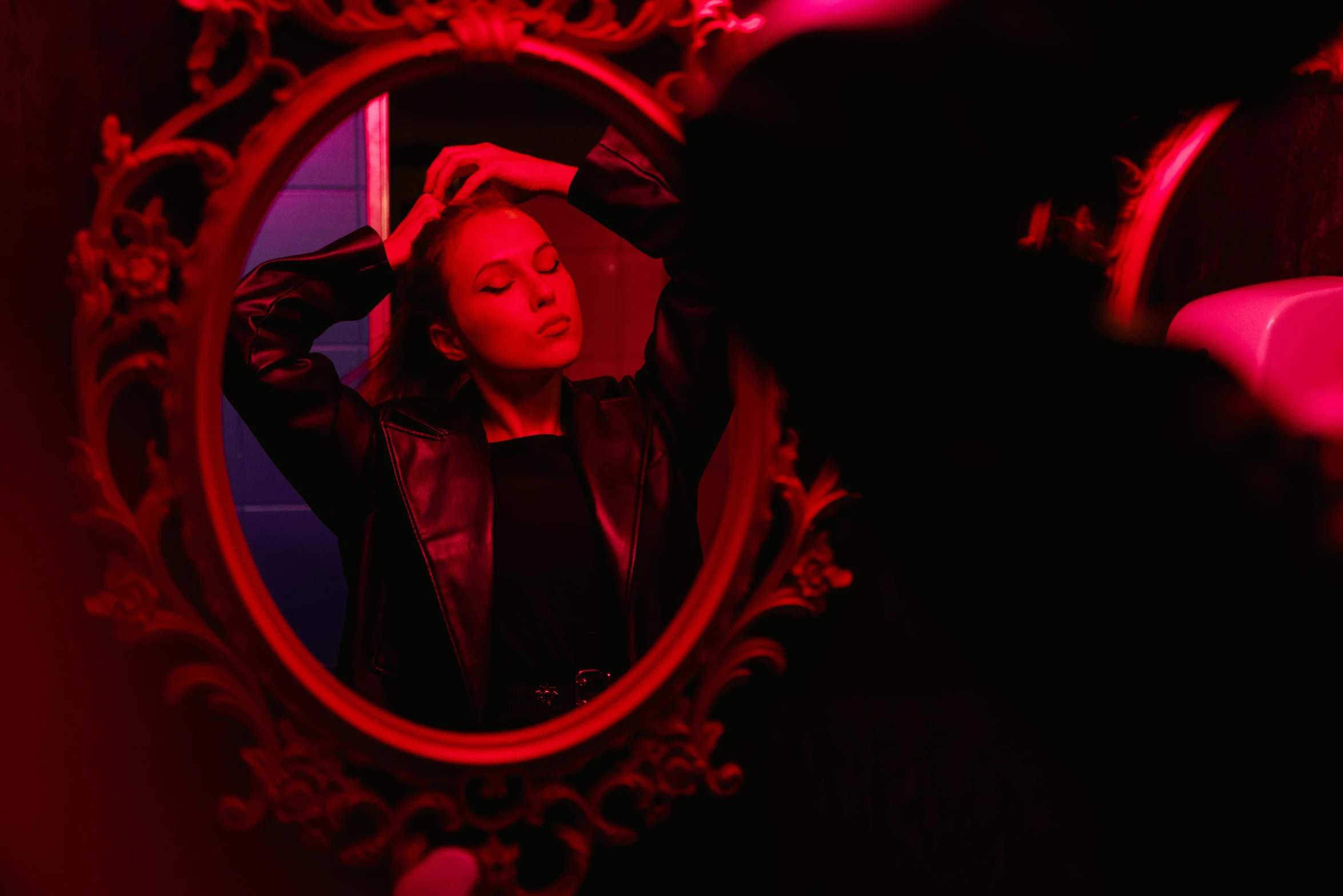 a woman combing her hair in front of a mirror, an album cover, inspired by Elsa Bleda, pexels contest winner, red and obsidian neon, portrait sophie mudd, red leather jacket, sydney sweeney
