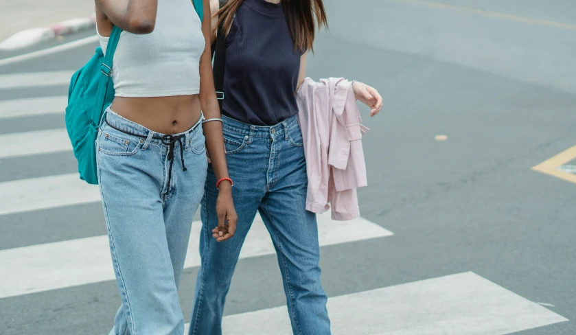 a couple of women walking across a street, trending on pexels, denim jeans, physical : tinyest midriff ever, pastel clothing, high quality product image”