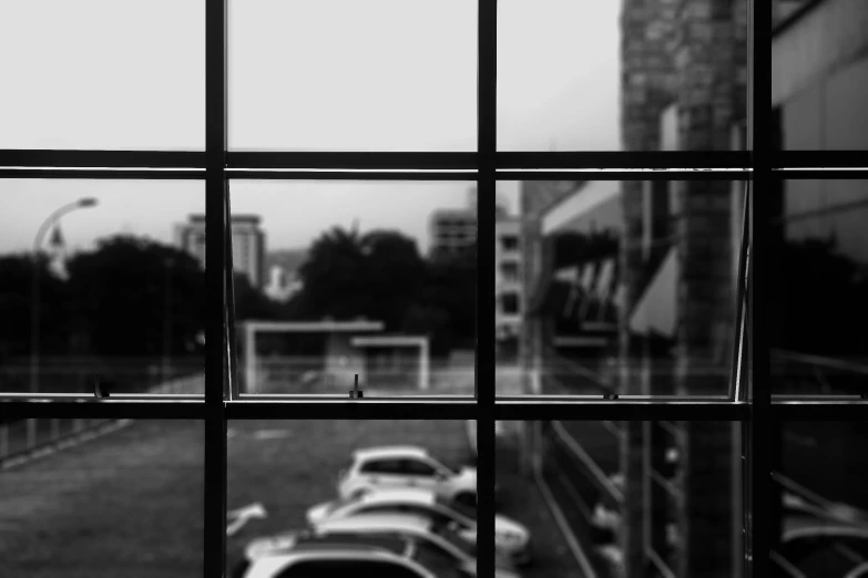 a view of a parking lot through a window, a black and white photo, by Ismail Acar, pexels contest winner, visual art, window and city background, :: morning, slightly pixelated, glass window