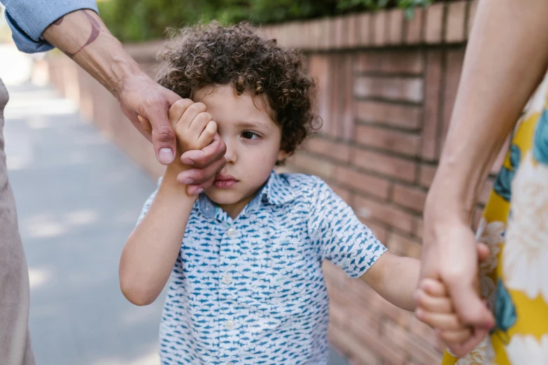 a close up of a person holding a child's hand, pexels contest winner, incoherents, boy with neutral face, portrait of family of three, walking boy, embarrassed