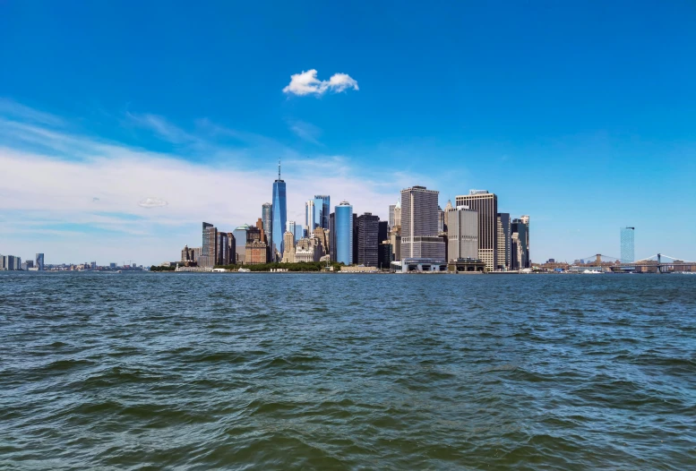 a large body of water with a city in the background, a picture, new york backdrop, clear blue skies, instagram post, high-resolution photo