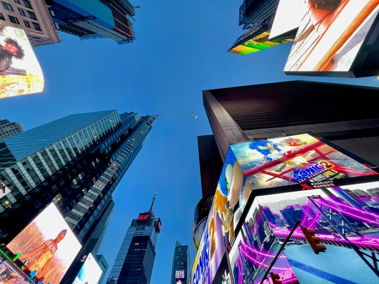 a city filled with lots of tall buildings, by Douglas Shuler, pexels contest winner, visual art, time square, seen from below, billboard image, blue sky