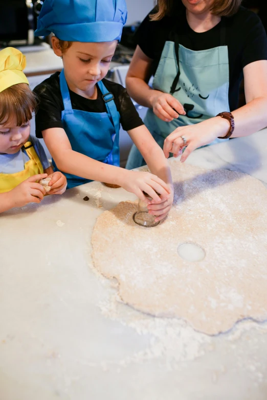 a woman and two children making dough in a kitchen, inspired by Caspar van Wittel, trending on pexels, process art, cutout, head down, chefs table, round