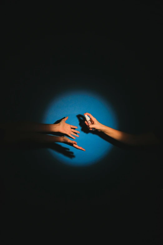 two hands reaching towards each other in the dark, an album cover, by Adam Marczyński, pexels contest winner, surrealism, with a blue background, flashlight on, toy photography, women hand