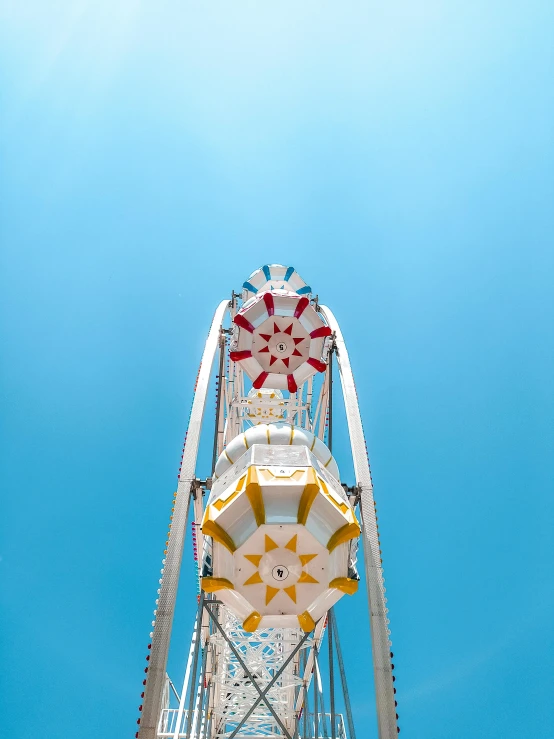 a ferris wheel against a bright blue sky, by Julia Pishtar, pexels contest winner, white and yellow scheme, portrait photo, colorful photograph, upsidedown