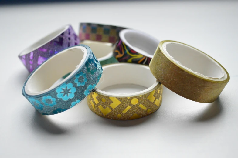 a group of rings sitting on top of a table, 40mm tape, patterned, glitter sticker, gold colours