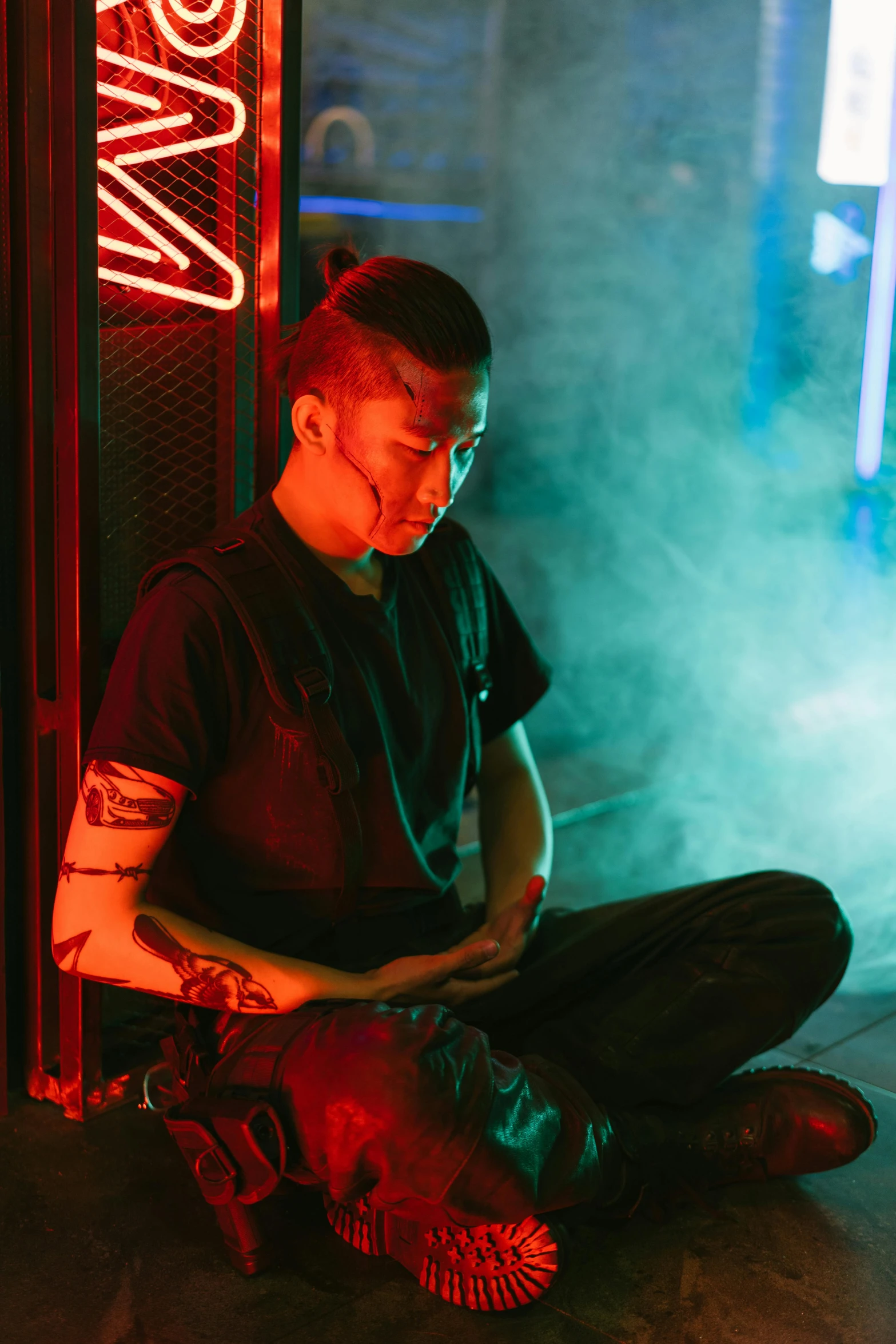 a man sitting on the ground in front of a neon sign, inspired by Liam Wong, symbolism, cyberpunk dyed haircut, praying, scene from bladerunner movie, wearing space techwear