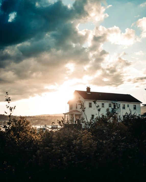 a white house sitting on top of a lush green field, inspired by Elsa Bleda, pexels contest winner, romanticism, sunlight through cumulus, seaside, golden hour cinematic, new england architecture