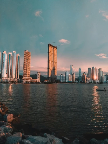 a large body of water with a city in the background, by Alejandro Obregón, pexels contest winner, hyperrealism, sunset panorama, tall metal towers, gif, colombia