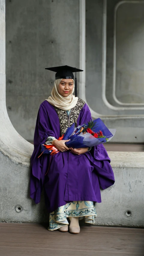 a woman in a graduation gown sitting on a ledge, by Basuki Abdullah, bouquet, wearing a head scarf, proud smirk, ap news photograph
