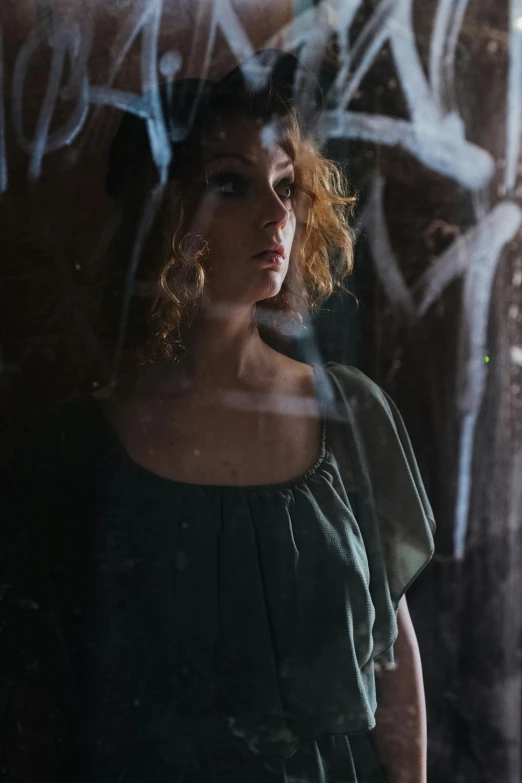 a woman standing in front of a graffiti covered wall, a portrait, inspired by Elsa Bleda, pexels contest winner, renaissance, window reflections, curly blonde hair | d & d, photography of todd hido, side portrait of imogen poots