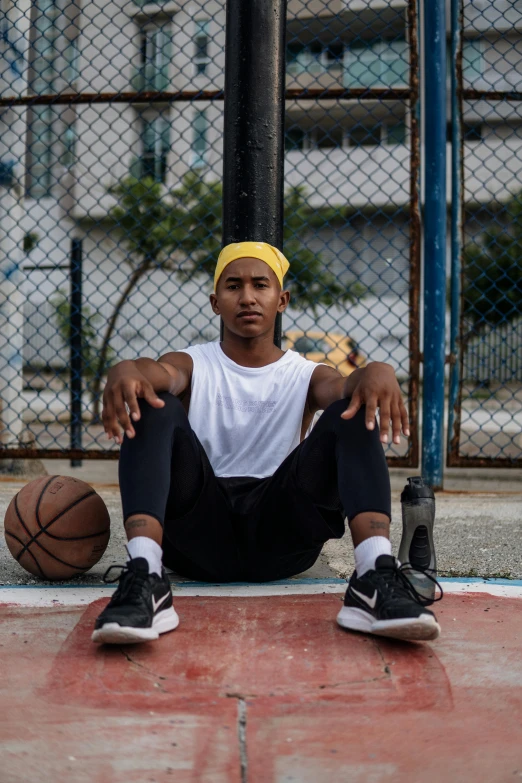 a man sitting on a basketball court holding a basketball, pexels contest winner, wearing a headband, in sao paulo, non-binary, street clothing