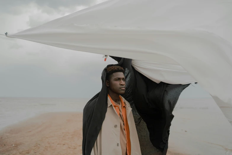 a man standing next to a horse on a beach, an album cover, by Lily Delissa Joseph, pexels contest winner, afrofuturism, he is wearing a trenchcoat, draped in flowing fabric, overcast, movie still 8 k