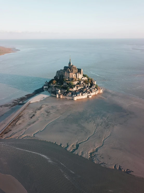 an aerial view of a small island in the middle of the ocean, unsplash contest winner, art nouveau, epic castle with tall spires, the normandy landings, intimidating floating sand, photo from 2022