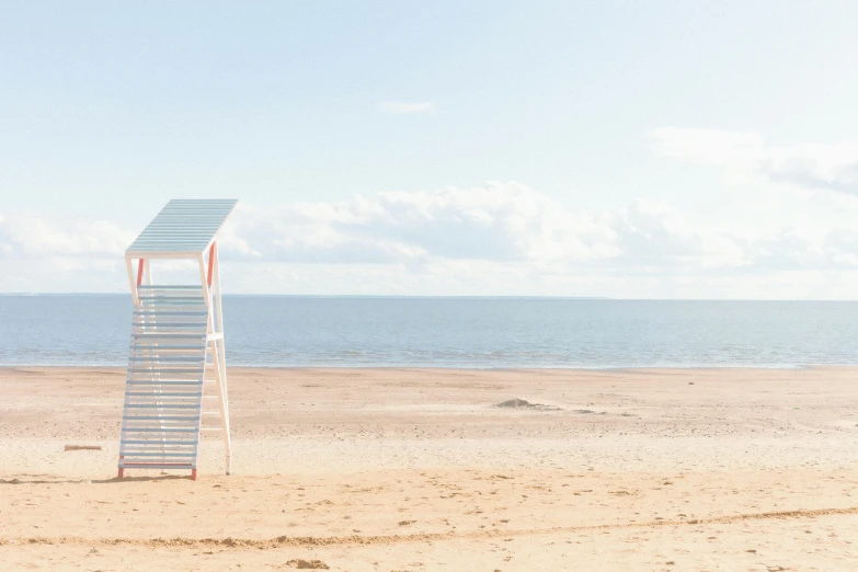 a lifeguard tower sitting on top of a sandy beach, a photo, by Rachel Reckitt, unsplash, minimalism, in a sun lounger, omaha beach, épaule devant pose, white