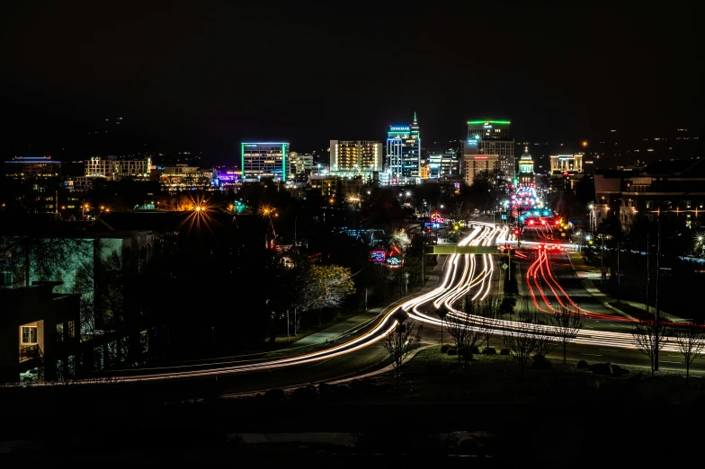 a view of a city at night from the top of a hill, by Dan Frazier, unsplash contest winner, visual art, albuquerque, traffic with light trails, square, with a black background