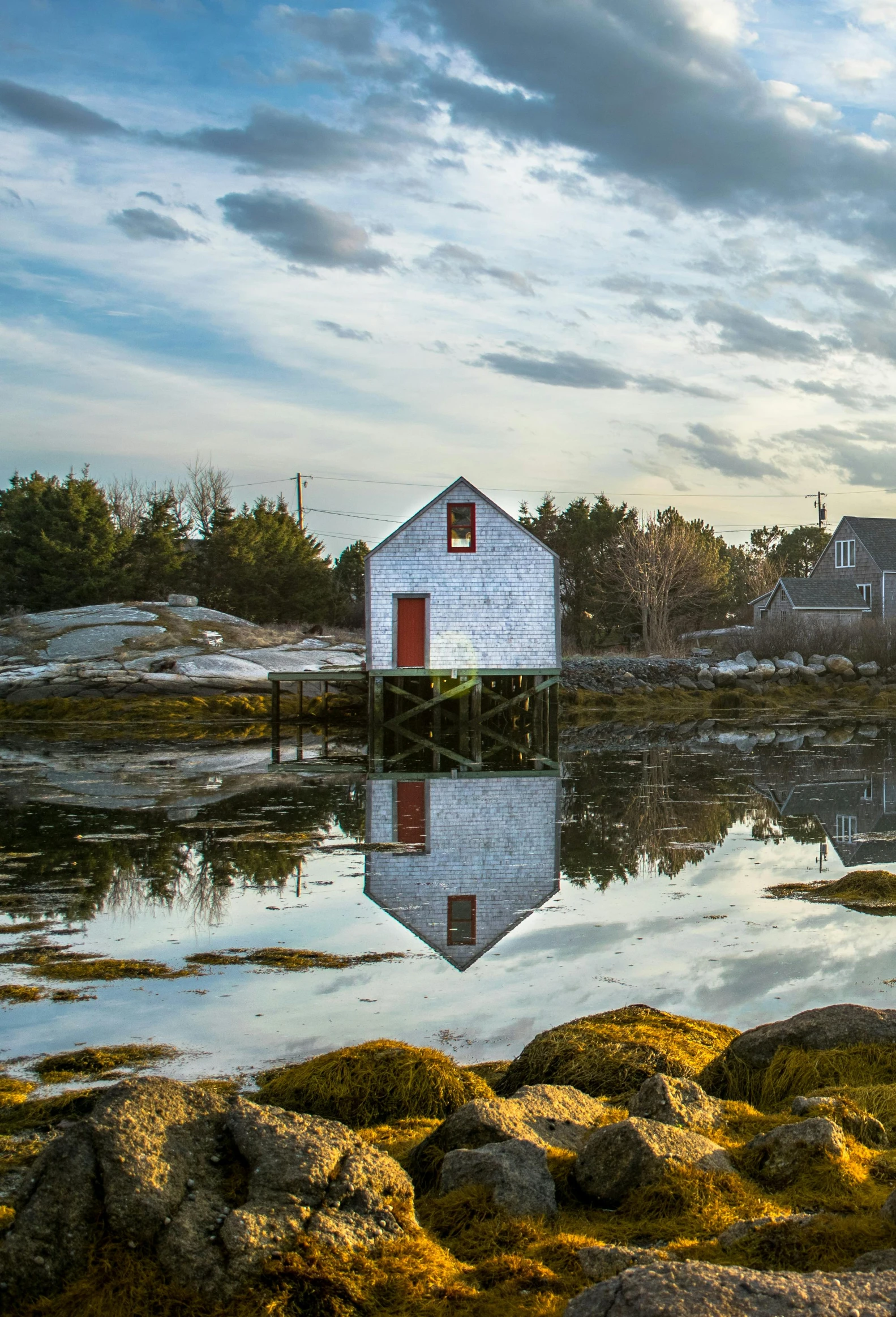 a small boat sitting on top of a body of water, by Jessie Algie, pexels contest winner, new england architecture, reflection on the oil, rustic stone cabin in horizon, slide show