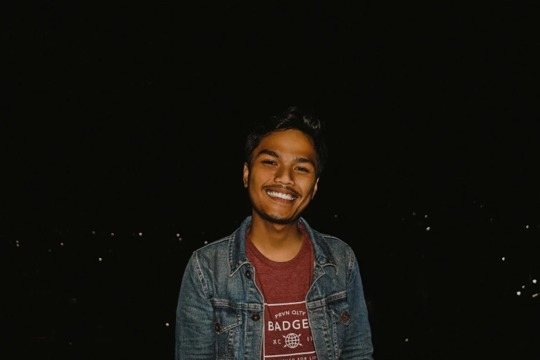 a man in a denim jacket smiles at the camera, a picture, by Byron Galvez, pexels contest winner, hurufiyya, calm night. over shoulder shot, assamese aesthetic, discord profile picture, in a medium full shot