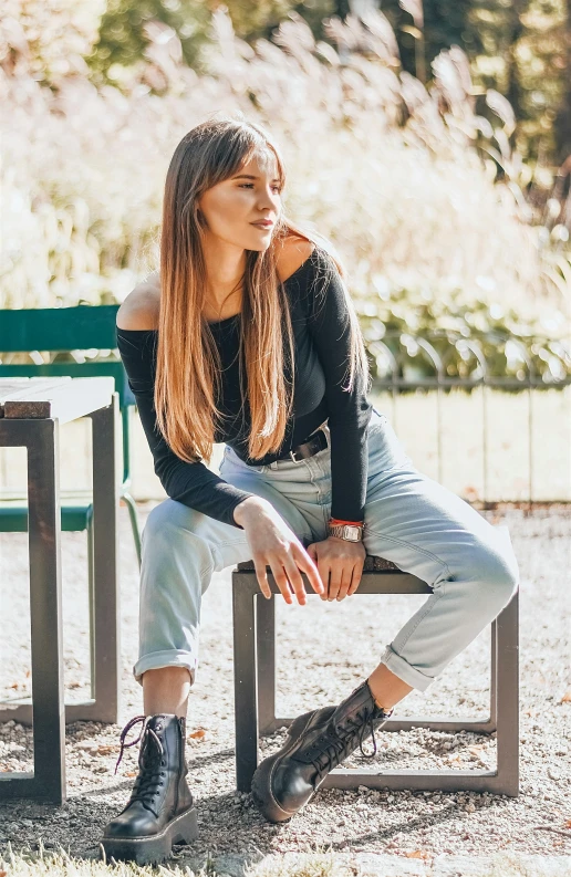 a woman sitting on a bench in a park, a portrait, trending on pexels, baggy jeans, full body:: sunny weather::, young with long hair, wearing a black sweater