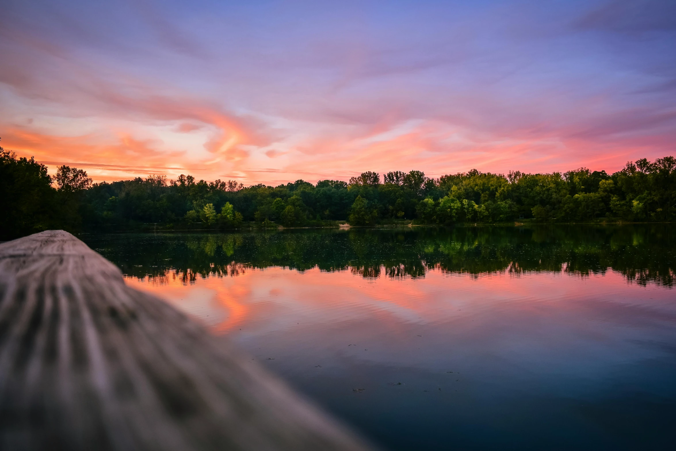 a dock that is next to a body of water, pexels contest winner, sunset colors, trees reflecting on the lake, from wheaton illinois, wide angle river