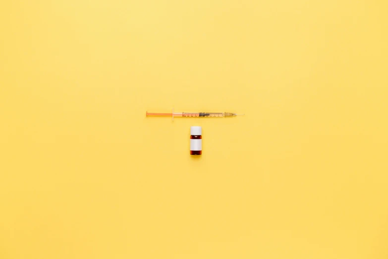 a pen sitting on top of a yellow surface, syringe, minimalist photorealist, shot from a drone, steroid use