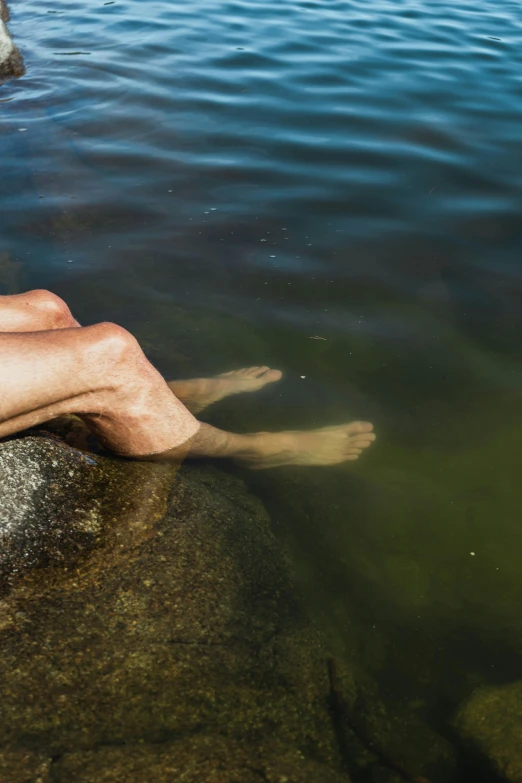 a man sitting on a rock in the water, by Jan Tengnagel, unsplash, realism, looks like varicose veins, nordic summer, female floating, minn