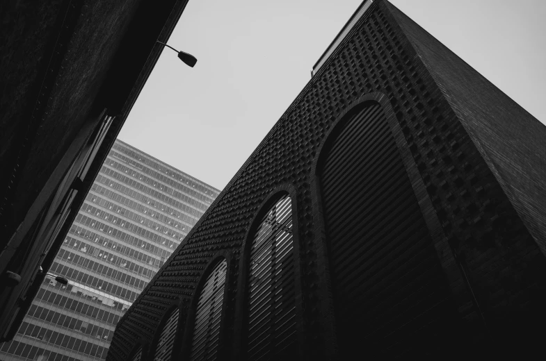 a black and white photo of a tall building, by Adam Rex, unsplash contest winner, alleyway, canary wharf, buildings covered in black tar, big arches in the back