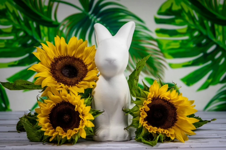 a white rabbit figurine sitting next to three sunflowers, inspired by Jeff Koons, pexels contest winner, glossy white metal, summer lighting, frontal shot, tropical mood