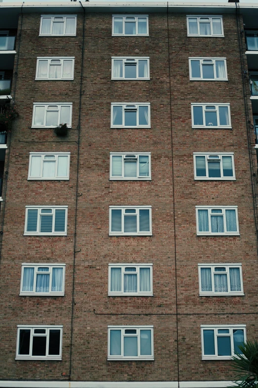 a tall brick building with lots of windows, inspired by Thomas Struth, unsplash, brutalism, grainy footage, martin parr, house windows, 8k 50mm iso 10