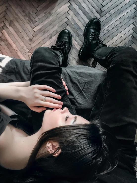 a close up of a person laying on a bed, inspired by Elsa Bleda, trending on pexels, aestheticism, gothic outfit, wearing tall combat boots, hand over mouth, profile image