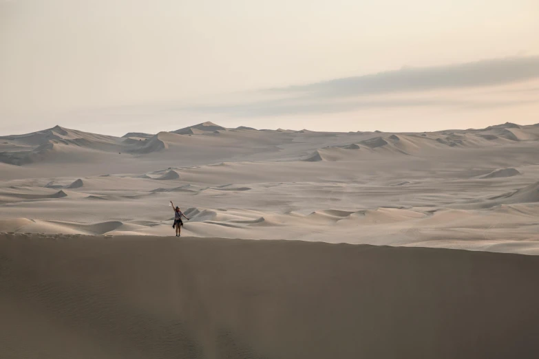 a man riding a snowboard down a snow covered slope, by Daniel Lieske, unsplash contest winner, walking over sand dunes, peru, sparsely populated, during dawn